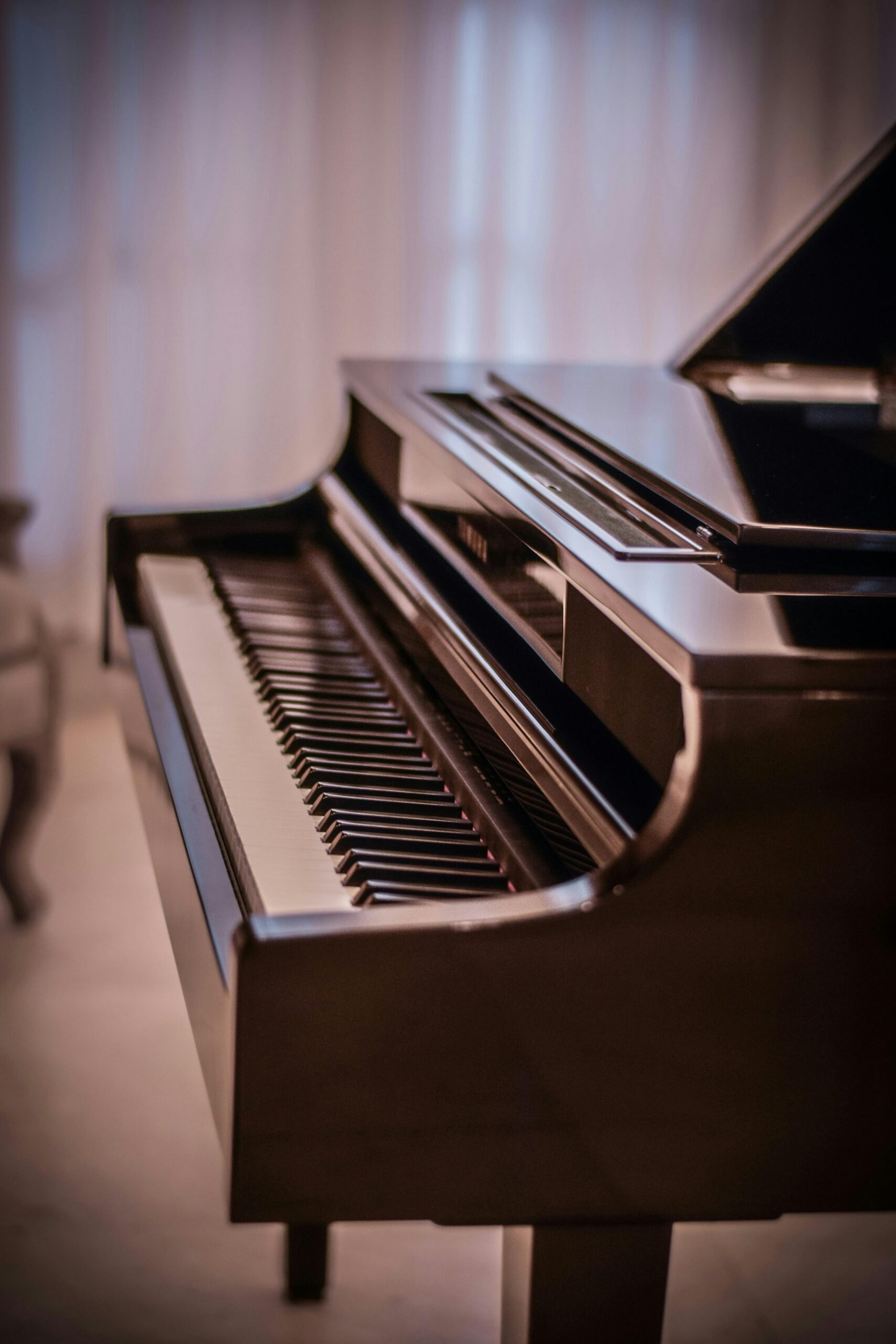 A close-up of a grand piano keyboard in soft ambient lighting, indoors.