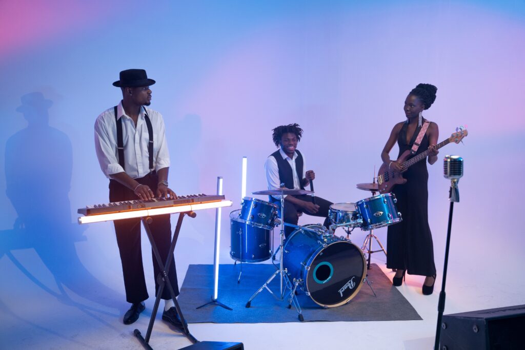 Apprendre A lively band performing with drums, keyboard, and bass guitar under colorful lights.